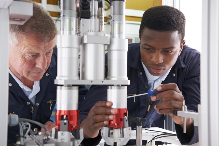 An engineer and T Level student fixing a factory machine.