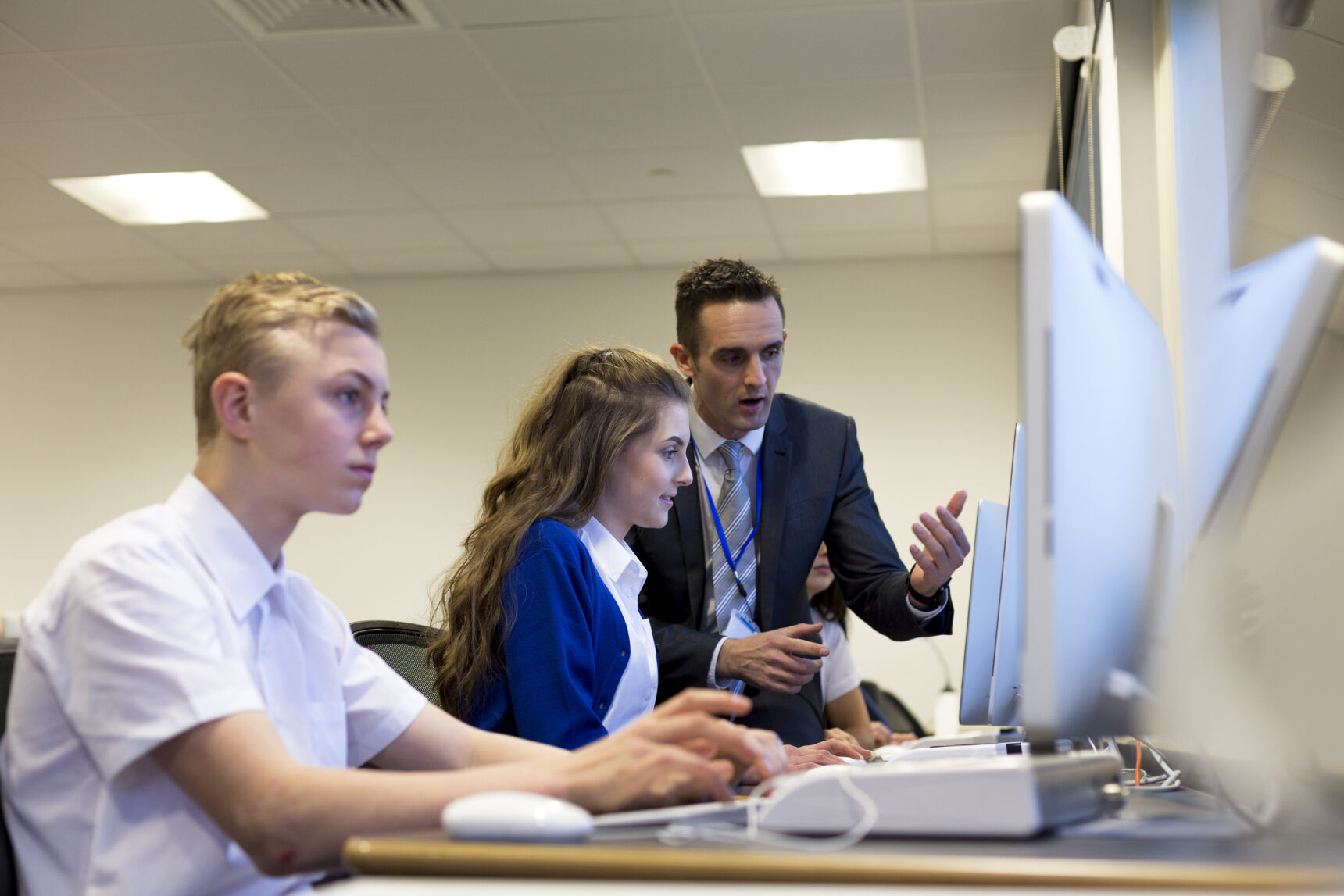 Male teacher looking at the Large Data Set on a computer with two students.