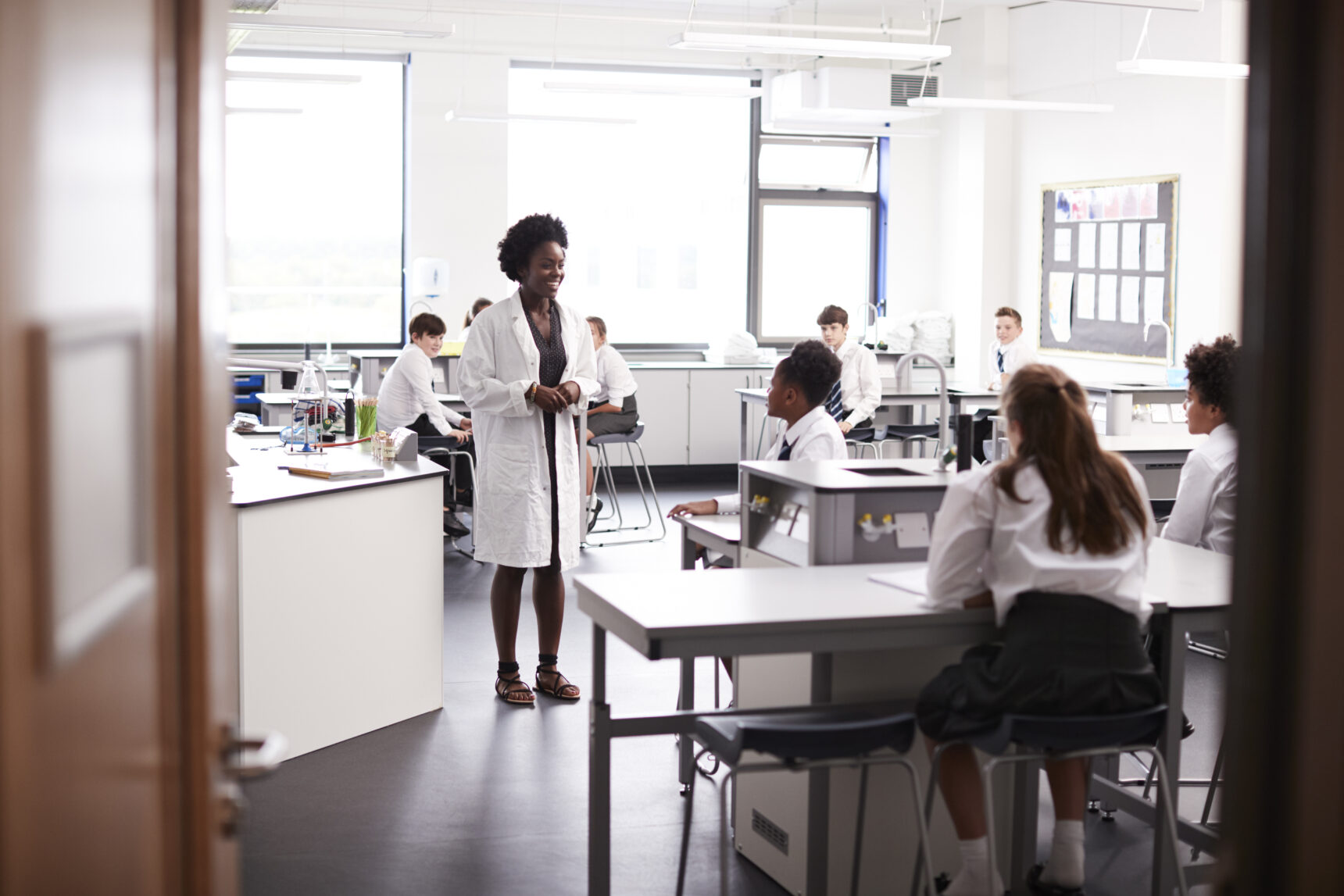 Female science teacher in laboratory coat addressing class.