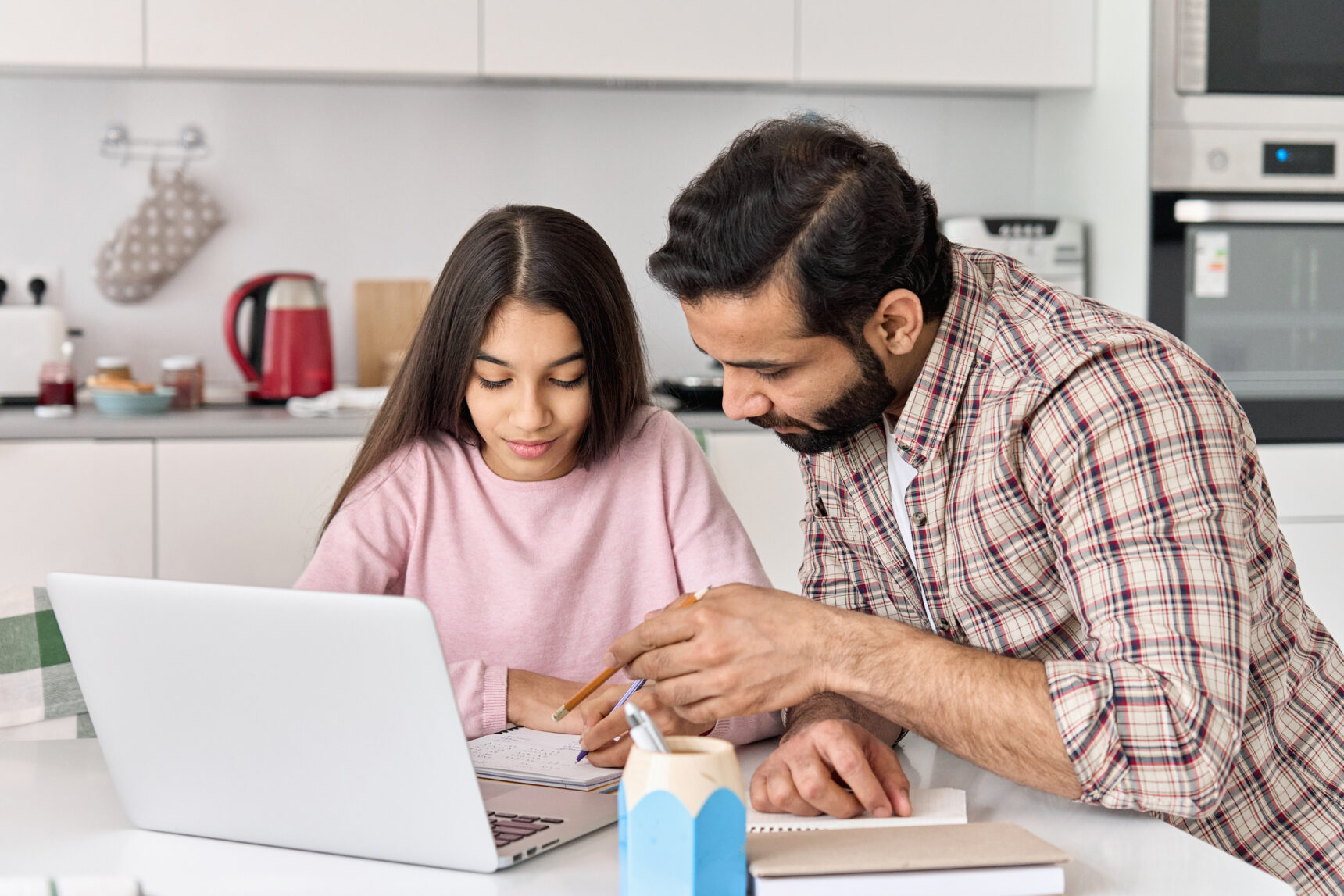 A father is helping his daughter with exam revision using the Physics and Maths Tutor website on a laptop.