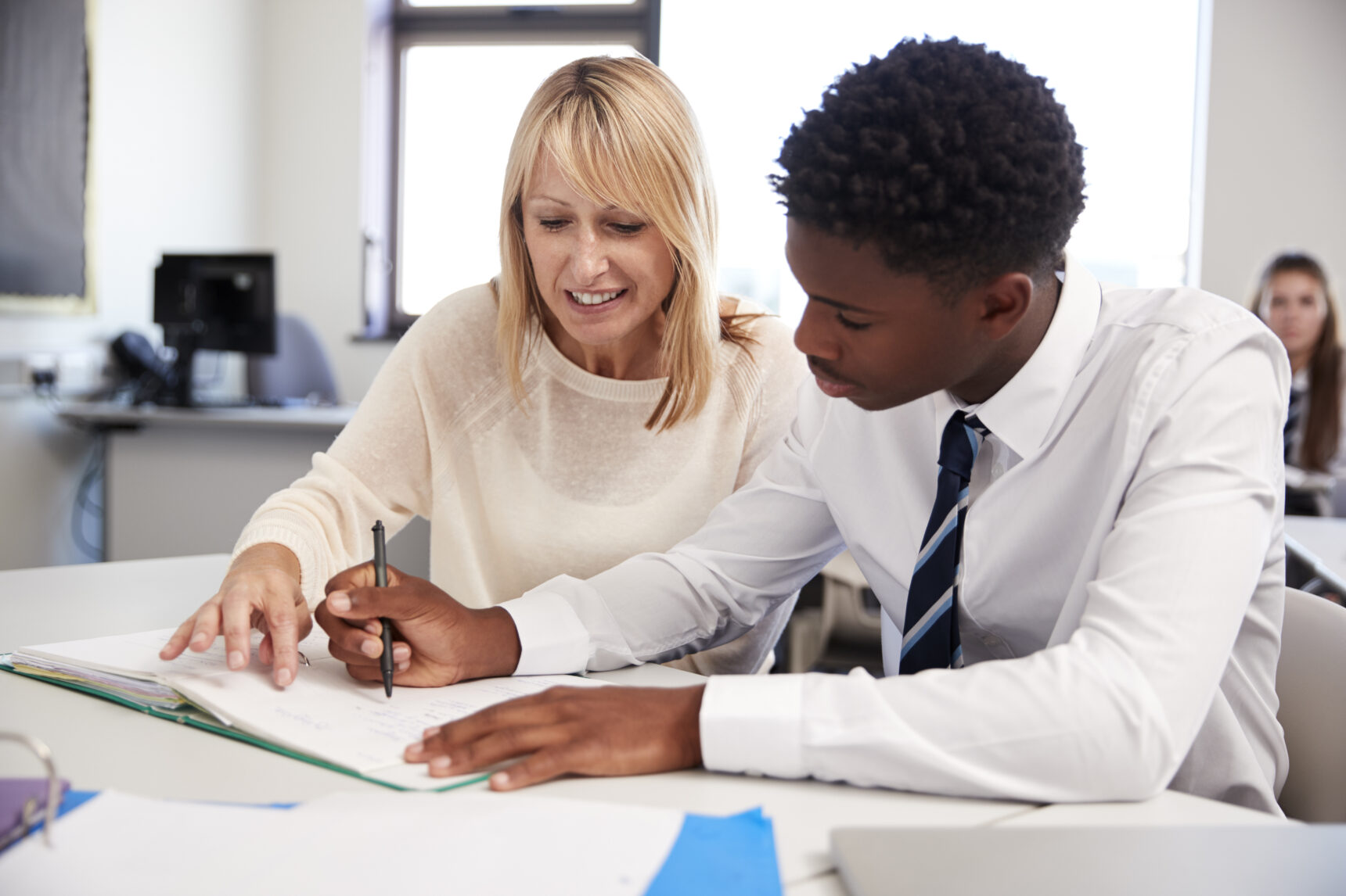 A teacher is giving feedback to a student on their assignment.