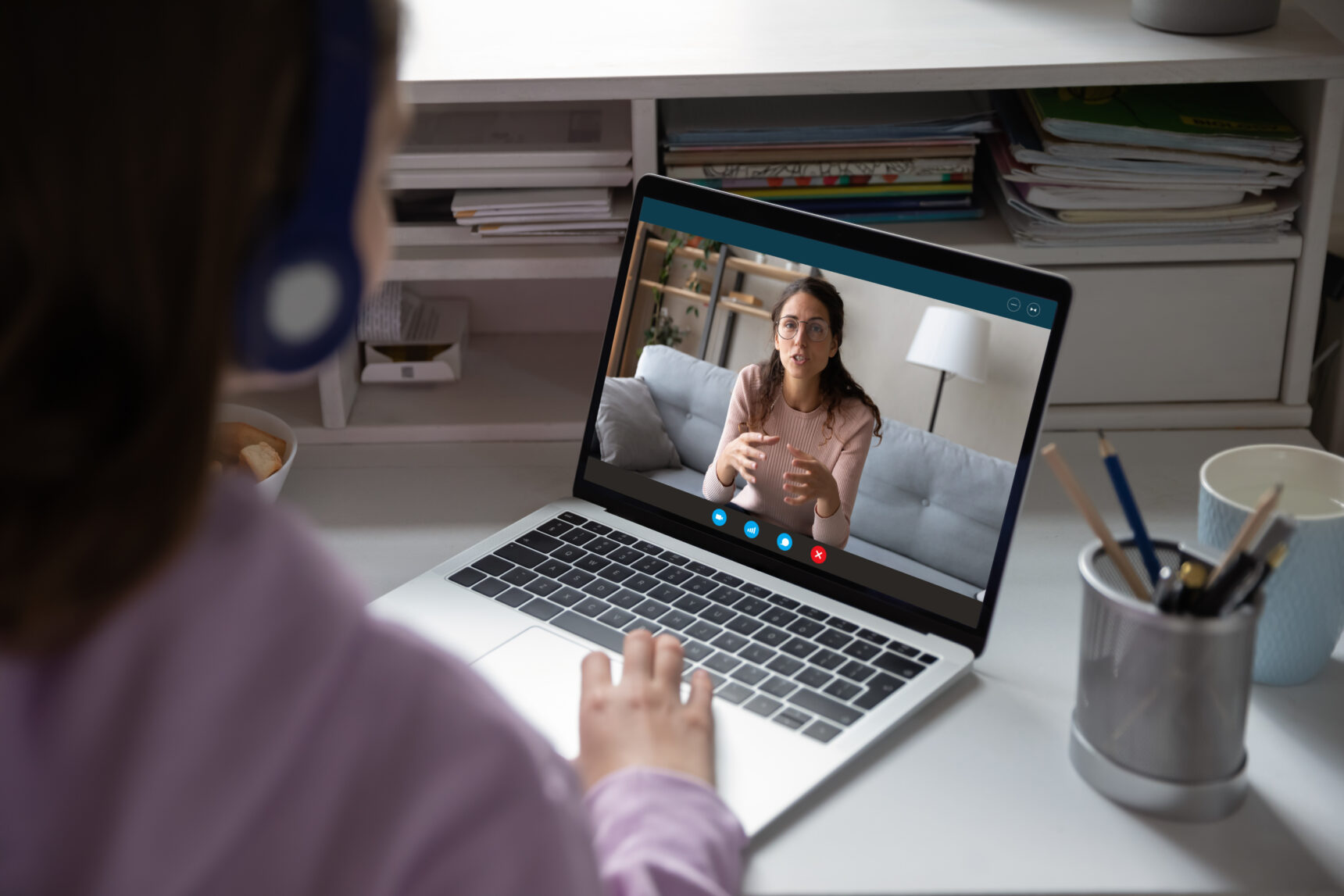 A young student wearing a headset is receiving tuition from an online tutor.