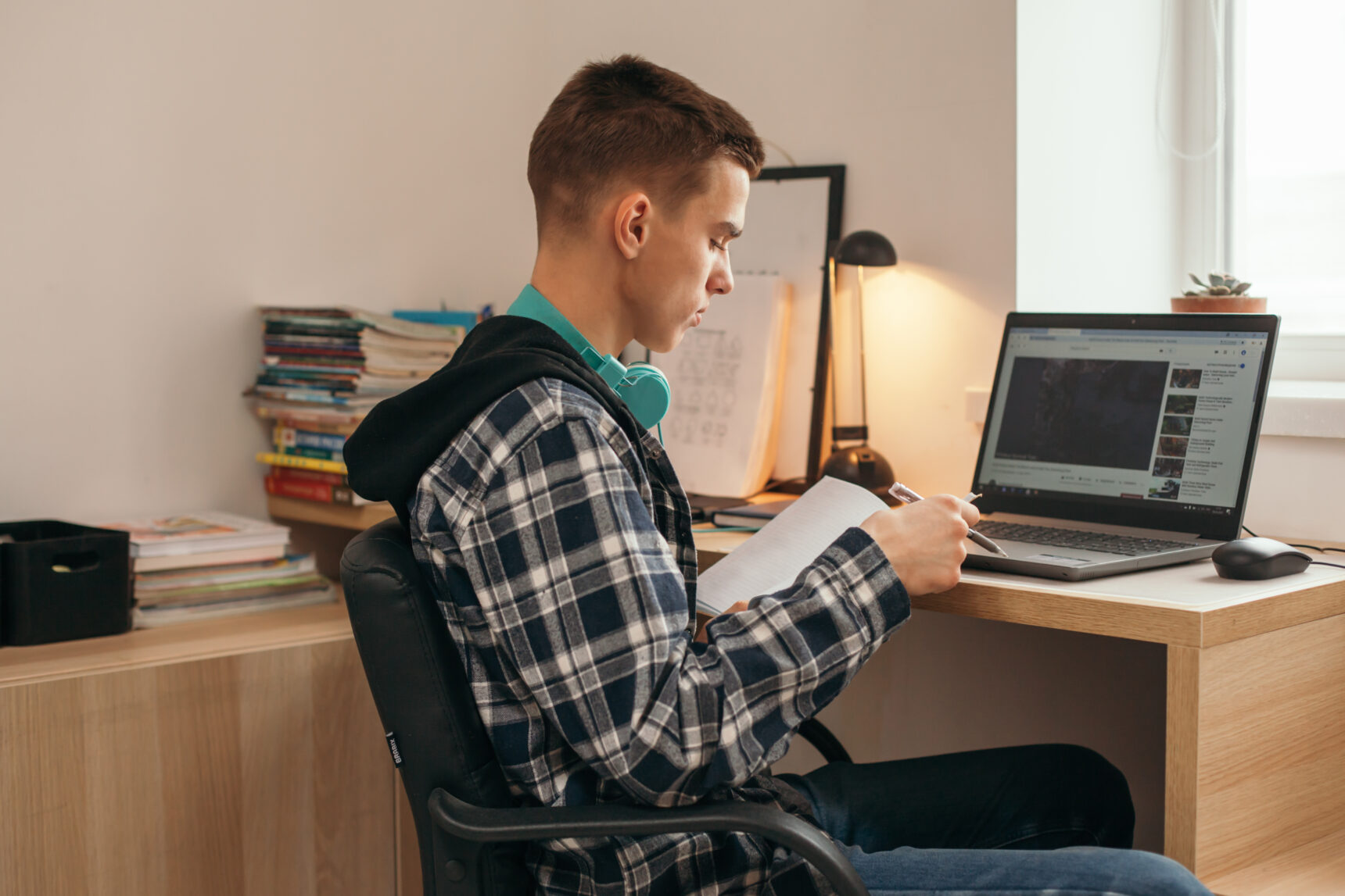 Teenage boy studying for GCSE exams at a bedroom desk with natural light.