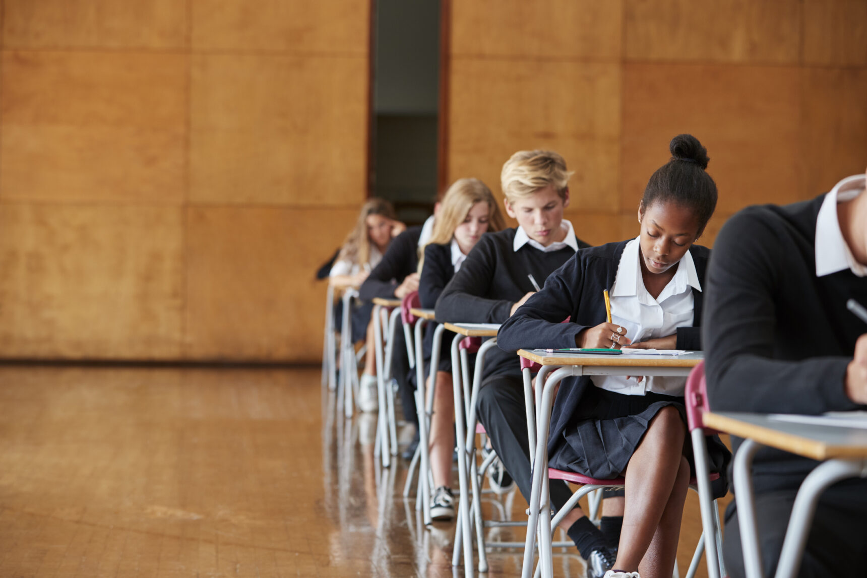 Students are sitting the AQA GCSE English Literature exam in an exam hall.