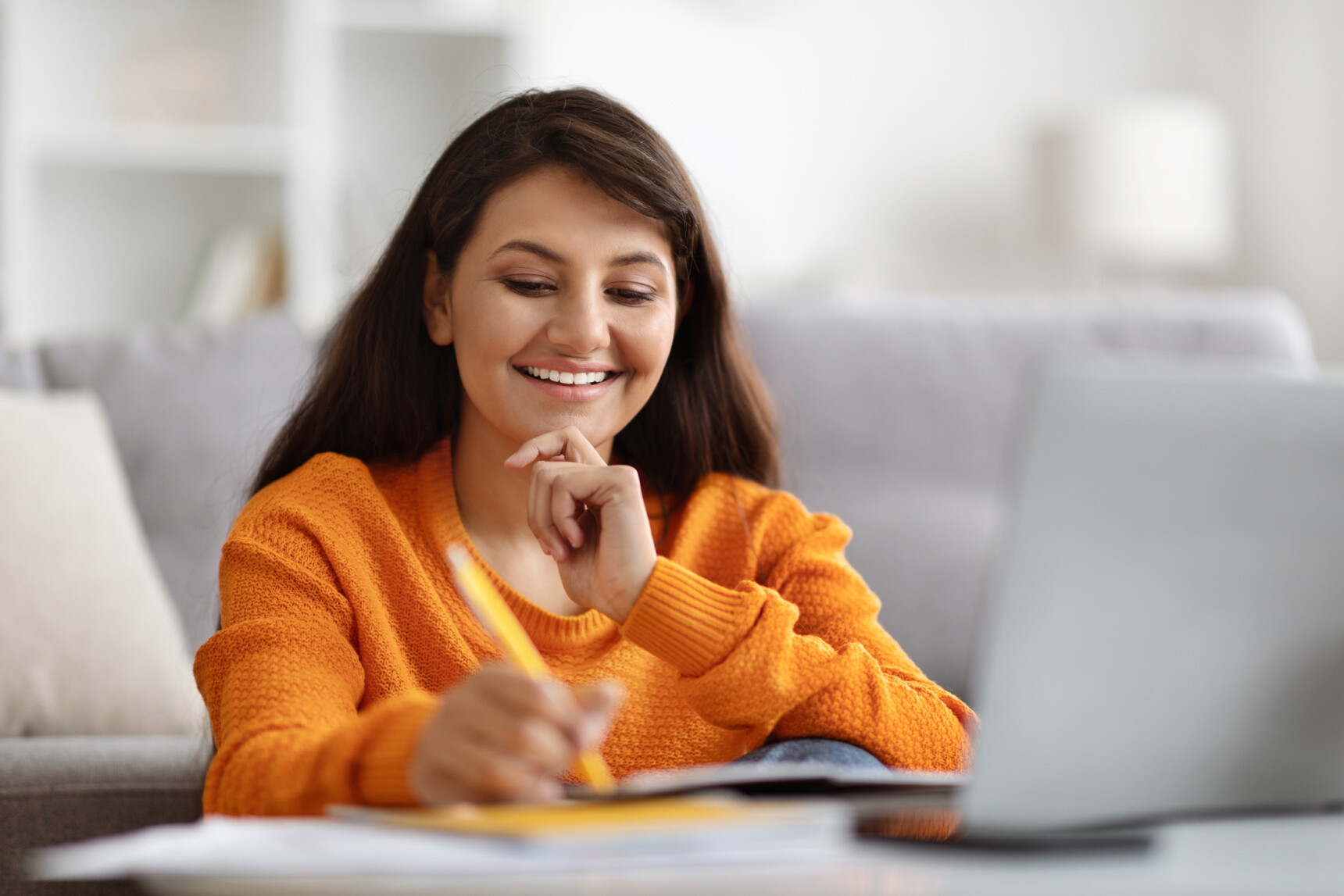 An English stduent is taking notes after receiving english essay feedback from her online tutor.