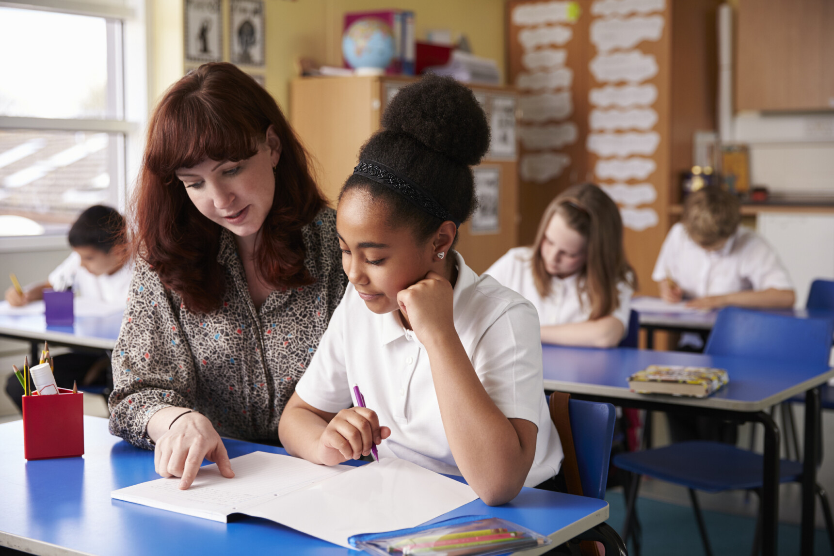 A teacher is supporting a dyslexic student in the classroom.